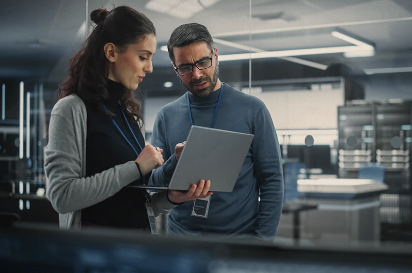 photo de 2 personnes qui regardent un ordinateur dans une salle de serveurs informatiques